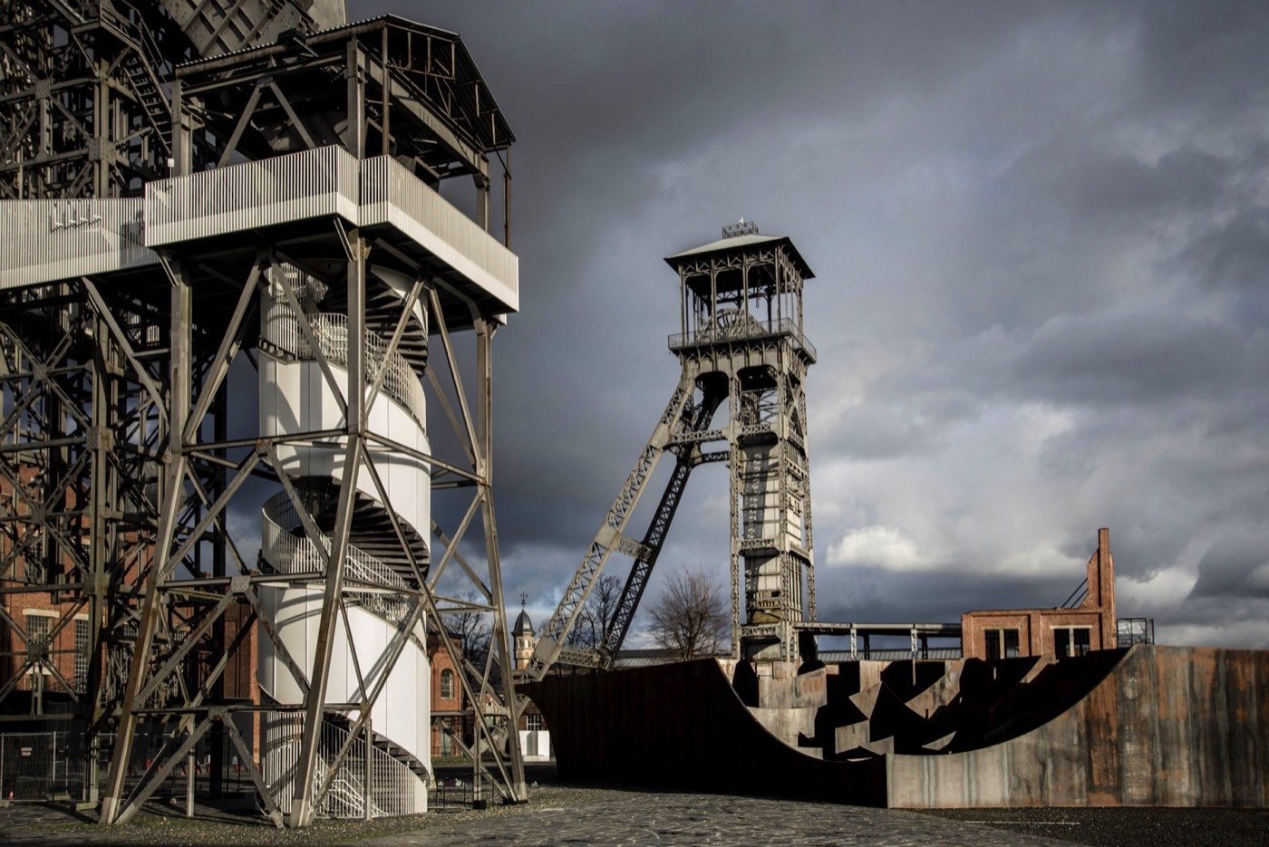 The two steel winding towers of the former Winterslag colliery at C-mine in Genk under a dark sky