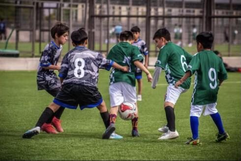 Young children playing a football match on a pitch in Mexico