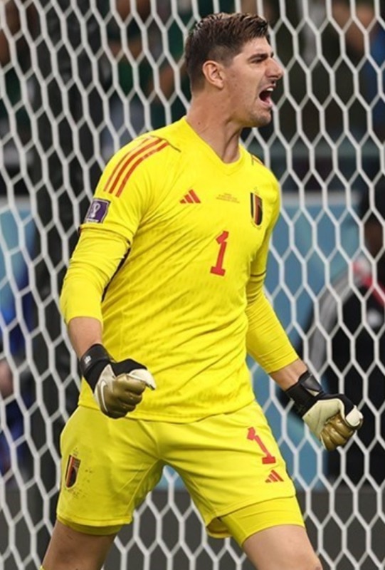Thibaut Courtois in Belgium's yellow goalkeeper shirt shouting in front of the net at the 2022 World Cup